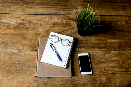 Working object notebook and pen with glasses and cell phone on wooden table.の写真素材