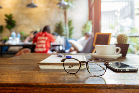 Selected focus eyeglasses and cell phone on wood table.の写真素材