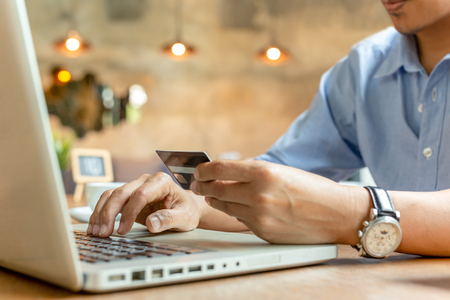 Man paying with credit card on laptop at coffee shop.の写真素材
