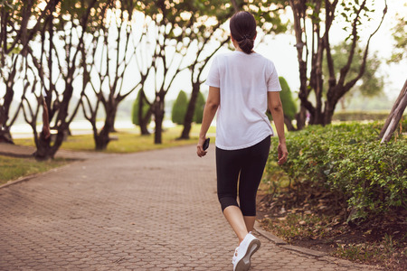Woman exercise walking in the park with hand holding cell phone in morning.の写真素材