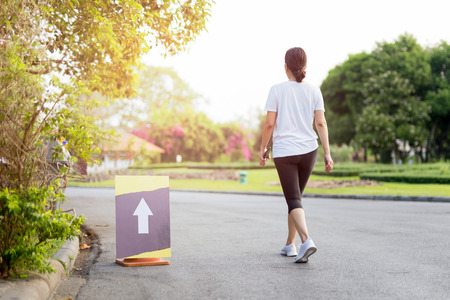 Woman exercise walking in the park with hand holding cell phone in morning.の写真素材