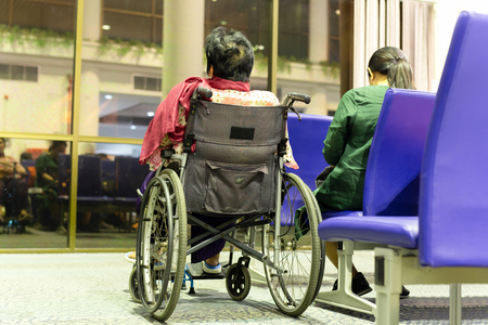 Senior woman in wheelchair with daughter at departure gate.の写真素材