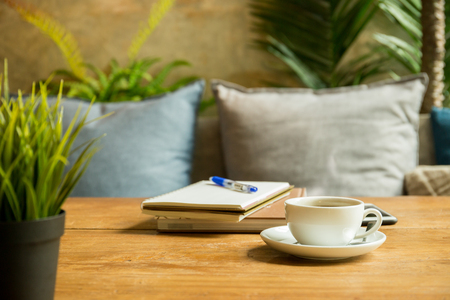 Cup of coffee with books and pen on wooden table in coffee shop.の写真素材