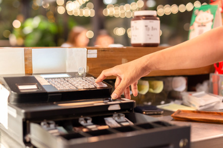 Shot in low light hand pressing electronic cash register in a shop.の写真素材