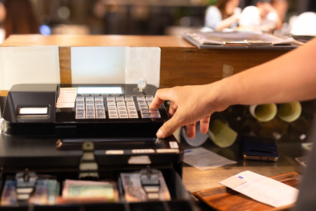 Shot in low light hand pressing electronic cash register in a shop.の写真素材