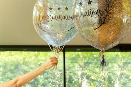 Hand holding balloons with  Congratulation text on it at party decoration.の写真素材