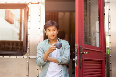 Portrait of asia man hand holding coffee cup relaxing on front door.の写真素材