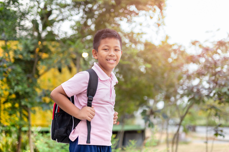 Happy asian school boy in uniform with backpack walking back home.の写真素材