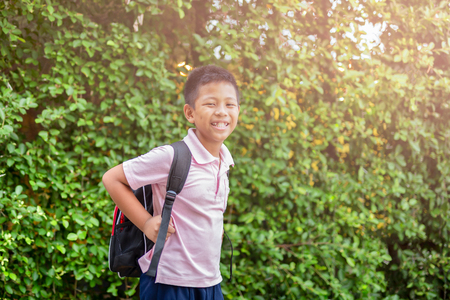 Happy asian school boy in uniform with backpack walking back home.の写真素材