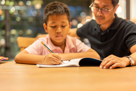 Boy doing homework with father at home.の写真素材
