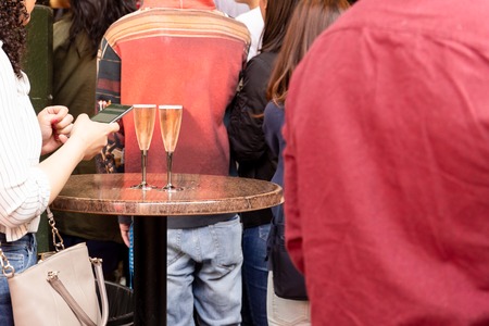 Woman using cell phone standing with glass of champagne in bar.の写真素材
