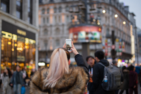 Woman tourist taking pictures of city with her cellphone in blurredの写真素材