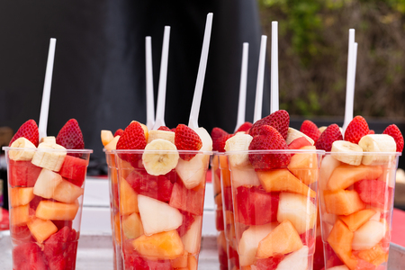 Mixed Fruit Salad arranged in plastic cups on a market stall.の写真素材