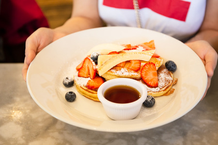 Woman hand holding breakfast meal of mixed fruits and maple syrup.の写真素材