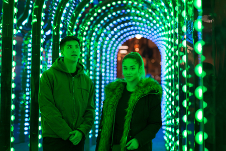 Portrait of mixed race teenage brother and sister standing in green neon light.の写真素材