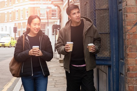 Happy mother with son walking on the street with takeaway coffee in there hands.の写真素材