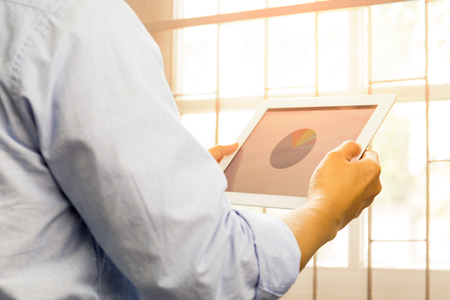 Business man working on the Tablet with stock market chart.の写真素材