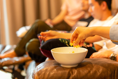 Woman hands taking popcorn from bowl watching movie with friend.の写真素材