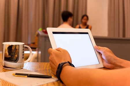 Businessman working on the tablet with friend in background.の写真素材