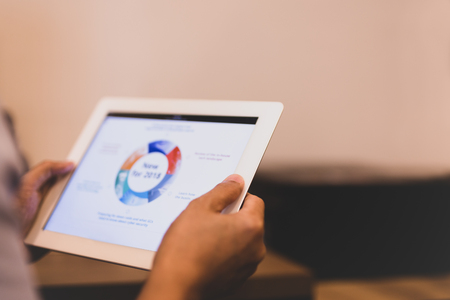 Man holding tablet with stock graph on screen in office.の写真素材