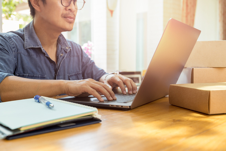 SME handsome businessman working on laptop with parcel on the table.の写真素材