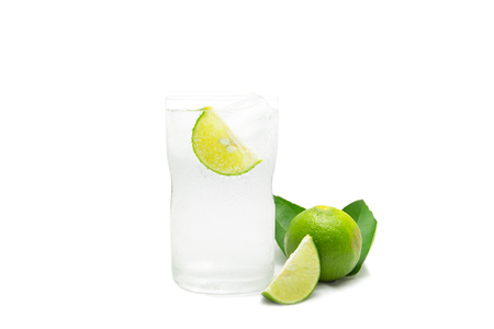 Glass of sparkling water soda with ice and lime slice on white background.の写真素材