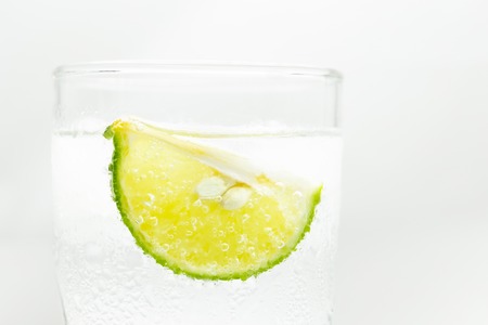 Glass sparkling water with ice cubes and slice of lime isolated.の写真素材