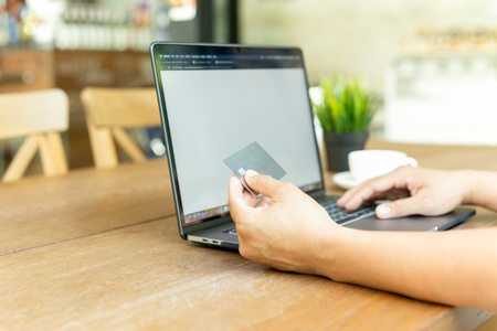 Businessman online working hand holding credit card and using laptop in cafe.の写真素材
