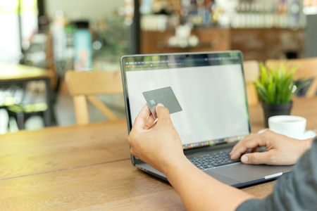 Businessman online working hand holding credit card and using laptop in cafe.の写真素材