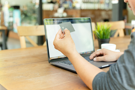 Businessman online working hand holding credit card and using laptop in cafe.の写真素材