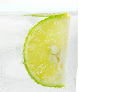 Close up slice of lime in glass sprakling water isolated.の写真素材