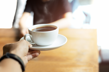 Waiter serving coffee to customer in coffee shop in the morning.の写真素材