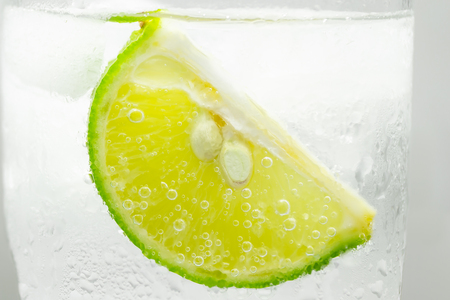 Close up slice of lime in glass sprakling water.の写真素材