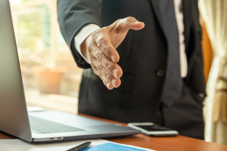 Businessman standing and reaching out hand for shaking.の写真素材