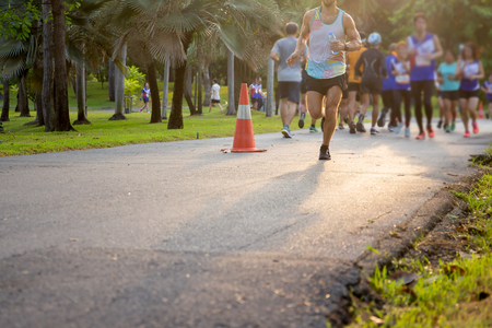 Man running in summer park with group of people in background.の写真素材