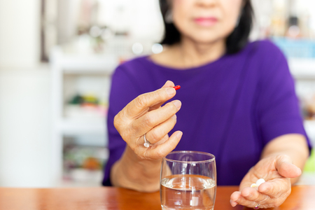 Senior woman hands holding tablet with glass of water on table.の写真素材