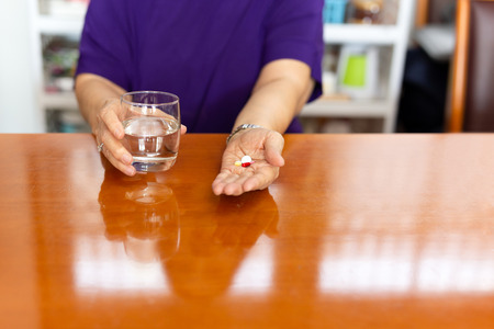 Senior woman hands with tablets and holding glass of water.の写真素材