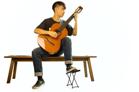 Asian man playing a classic guitar isolated in whiteの写真素材