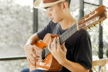 Asian man playing a classic guitar with his eye close.の写真素材