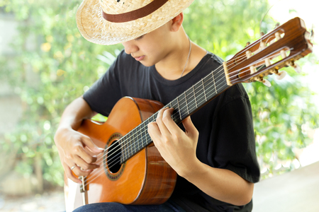 Asian man playing a classic guitar in nature.の写真素材