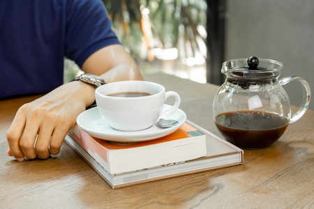 Man sits on table with coffee on the book in coffee shop.の写真素材