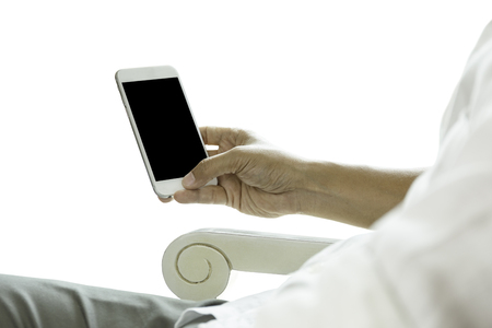 Man sit on chair looking at his cell phone isolated in clipping path,の写真素材