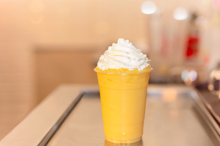 Fresh orange smoothie in plastic glass with cream on top.の写真素材
