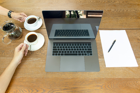 Top view of businessman hands holding coffee cup with laptop on tableの写真素材