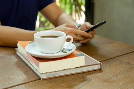 Man using cell phone with cup of coffee on table in cafeの写真素材