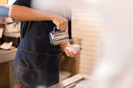 Barista hand pour milk making latte art coffee at cafe.の写真素材