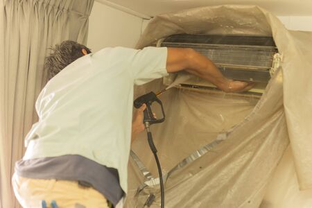 Worker cleaning wall air conditioner with high pressure water jet pump at home.の写真素材