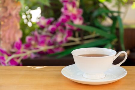 Cup of tea on wooden table in garden with blurの写真素材