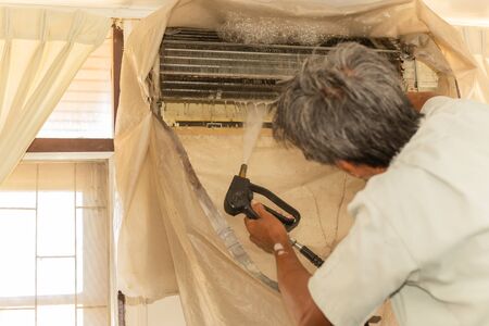 Worker cleaning wall air conditioner with high pressure water jet pump at home.の写真素材