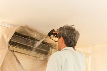 Worker cleaning wall air conditioner with high pressure water jet pump at home.の写真素材